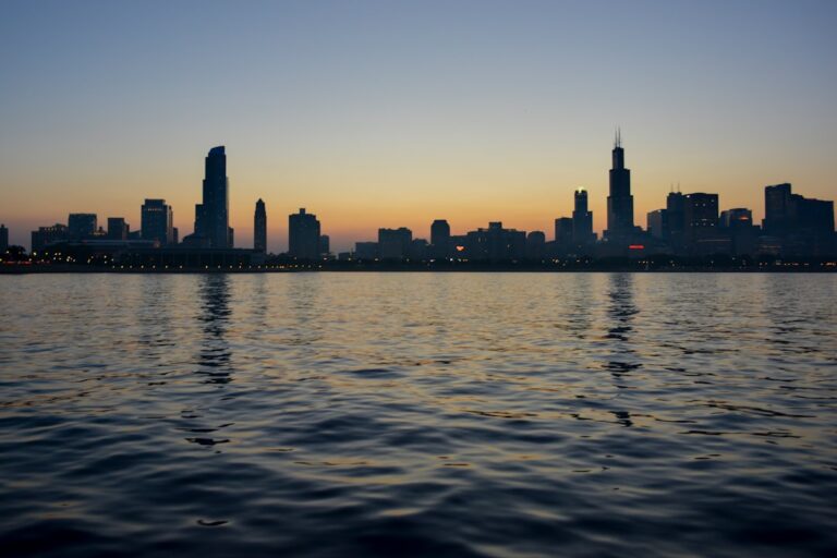 City skyline at sunset with calm waters, symbolizing the serene and high-quality service of Gramercy Cleaners, the best in your city.