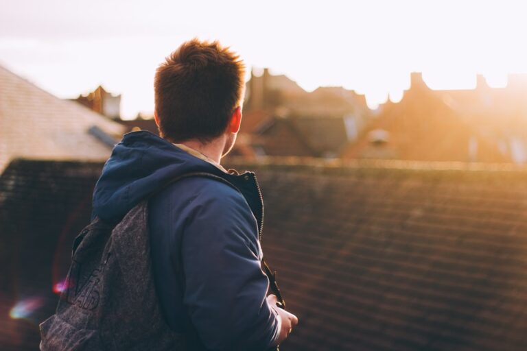 A person in a jacket with a backpack looks over a cityscape at sunset, symbolizing a clean, stress-free urban lifestyle in New York.